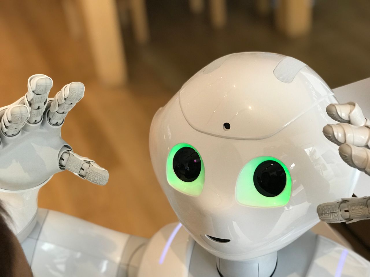 About A futuristic humanoid robot with glowing green eyes in a modern setting.